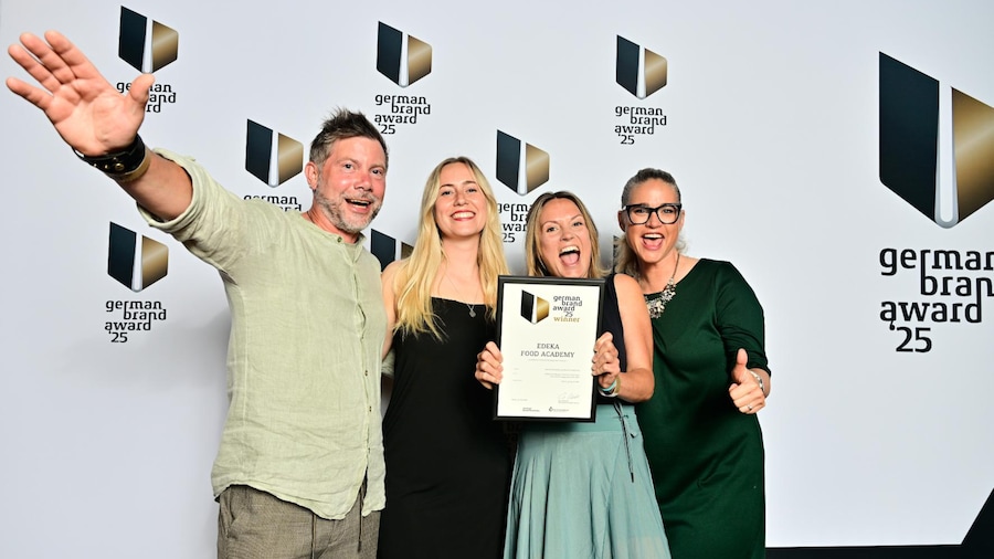 Ein Mann und 3 Frauen stehen vor einer Preisverleihungswand. Eine davon hat die Urkunde zum German Brand Award in der Hand.