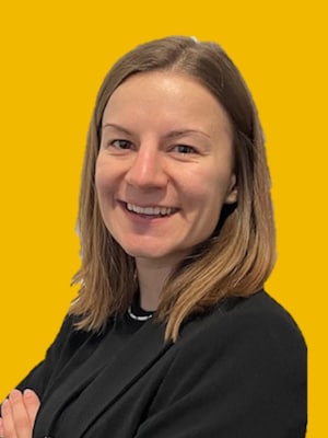 Portrait von Melanie Roth, lächelnde Frau mit schulterlangem braunem Haar vor gelbem Hintergrund