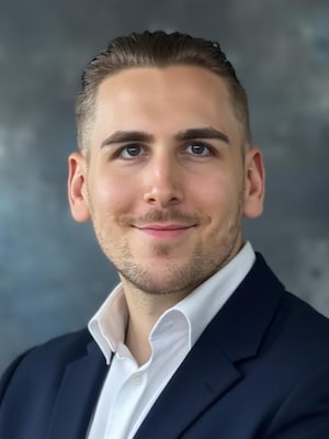 Portrait Maximilian Schramm - Mann mit weißem Hemd und Jacket lächelt