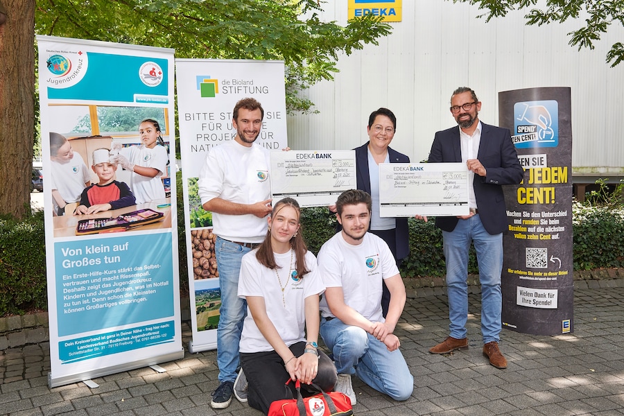 5 Personen präsentieren sich mit symbolischen Schecks vor den Bannern der Initiativen