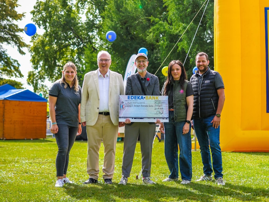 3 Männer und zwei Frauen stehen auf der Wiese und posen in die Kamera. Ein strahlender Mann hält einen symbolischen Scheck. 