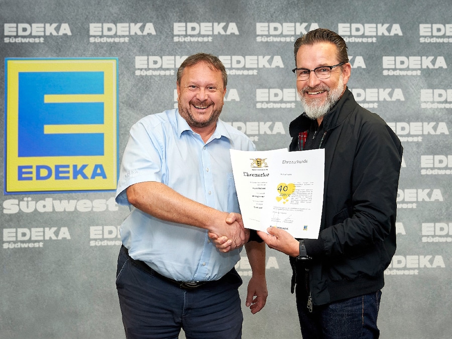 Ein Mann mit Urkunde gratuliert dem Jubilar.