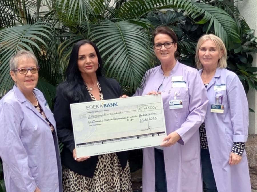 4 Frauen stehen vor einer großen Palme mit einem symbolischen Spendenscheck in der Hand.