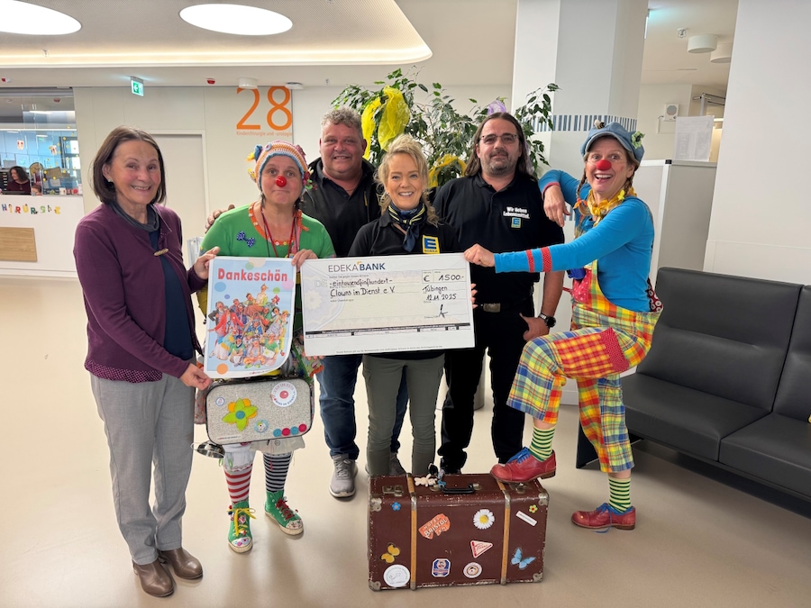 2 als Clowns gekleidete Frauen, stehen mit 4 Personen auf einer Krankenstation und halten einen Scheck und ein Dankesplakat
