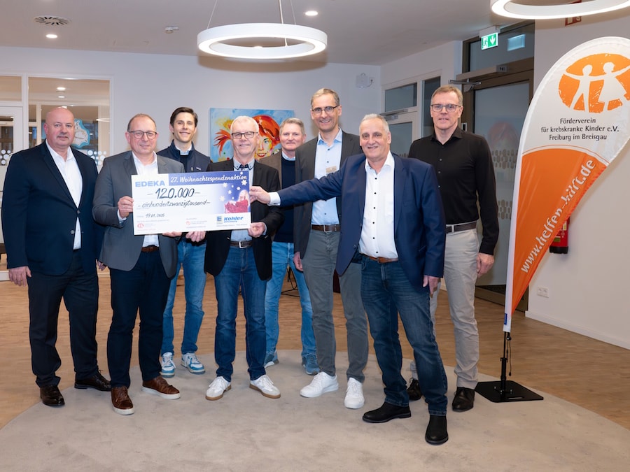 8 Personen präsentieren einen symbolischen Scheck.