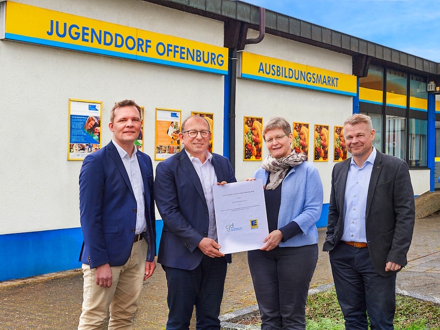 3 Männer und eine Frau stehen draußen vor dem Jugenddorf Ausbildungsmarkt, 2 Personen halten gemeinsam eine Urkunde 