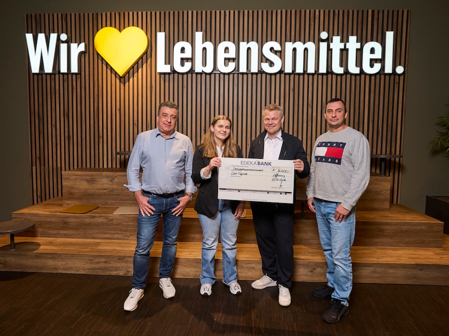 3 Männer und eine Frau stehen nebeneinander, 2 Personen halten einen symbolischen Spendenscheck