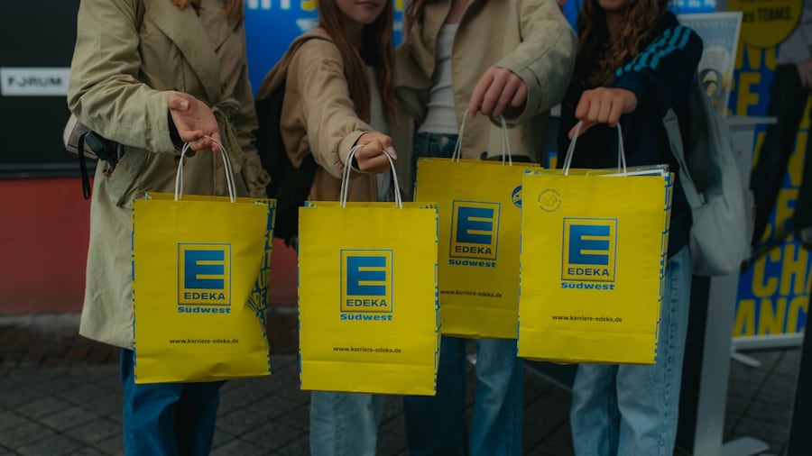 4 Menschen halten je eine gelbe EDEKA Südwest-Papiertasche