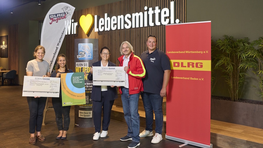 Fünf Personen vor Banner mit Schecks