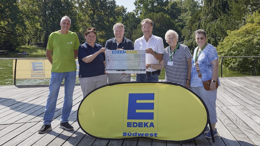 Sechs Personen auf einem Steg mit Scheck und EDEKA-Banner