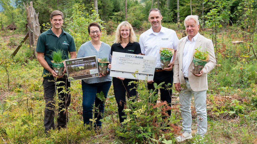 Fünf Personen im Wald mit Kräutertöpfen und Spendenscheck