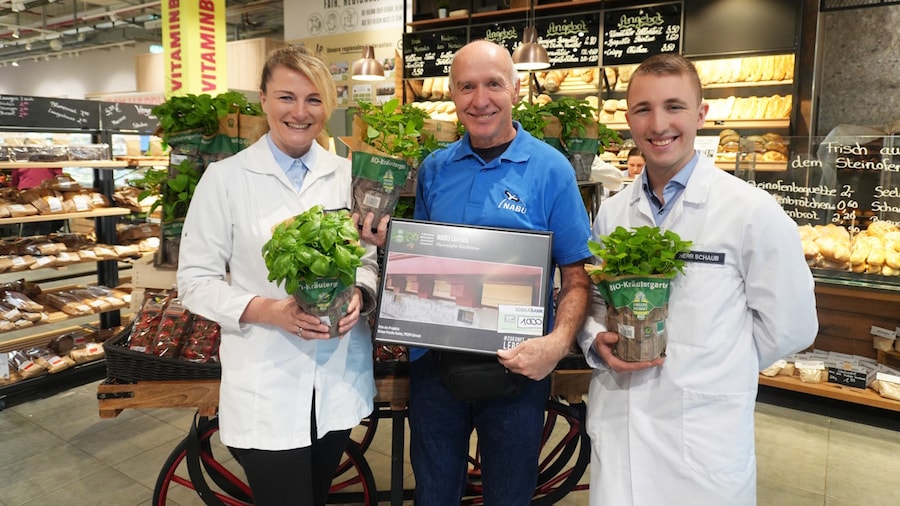Drei Personen im Markt mit Kräutertöpfen