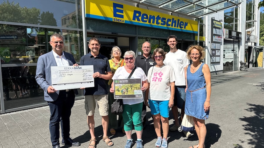 Acht Personen mit Scheck vor EDEKA-Markt
