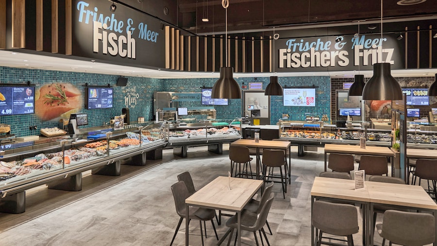 Frischeabteilung für Fisch und Meeresfrüchte mit Theke und Bistro-Sitzplätzen.