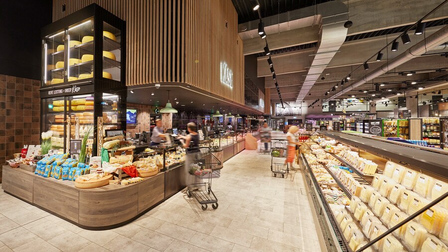 Käseabteilung im Supermarkt mit Bedientheke und großer Selbstbedienungs-Kühltheke