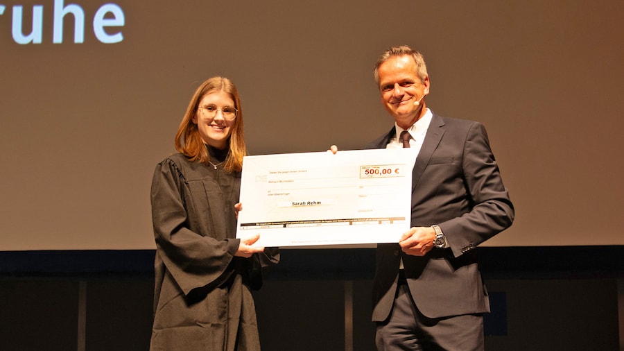 Preisträgerin und Vorstand Dr. Ralph Weber posieren mit übergroßem Spendenscheck über 500 Euro.