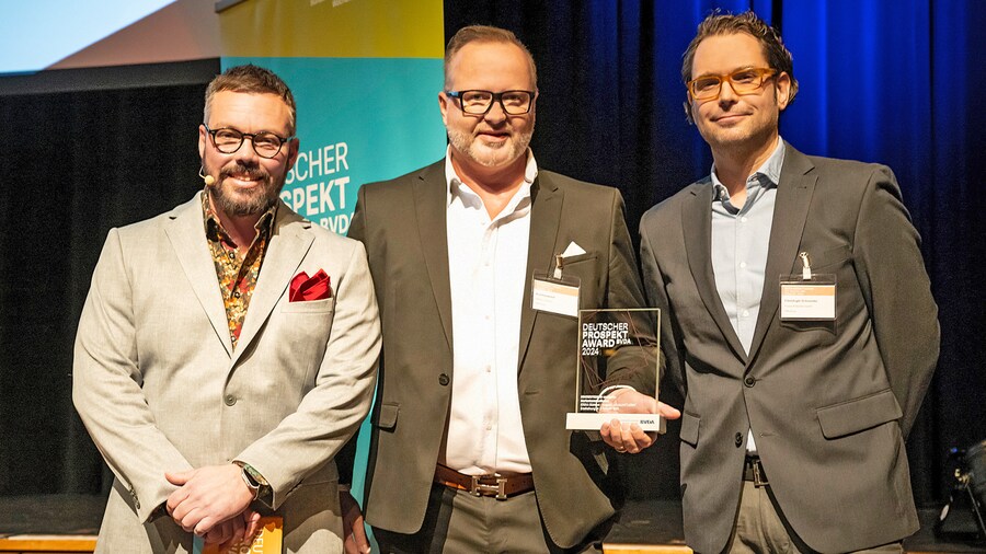Drei Männer posieren mit Glastrophäe mit der Aufschrift „Deutscher Prospekt Award“.