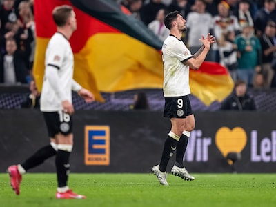 Zwei Fußballspieler der Deutschen Männer-Nationalmannschaft auf dem Spielfeld vor jubelnder Menge. 