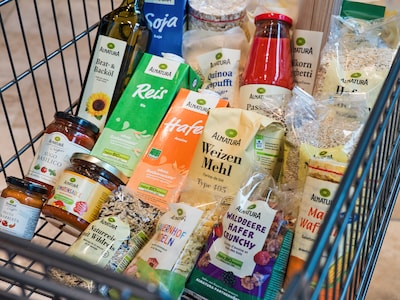 Nahaufnahme von vielen verschiedenen Alnatura-Produkten in einem Einkaufswagen. 