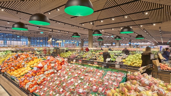 Kundinnen und Kunden stehen zwischen den Gondeln mit frischen Obst in der Obstabteilung eines großen EDEKA-Marktes.