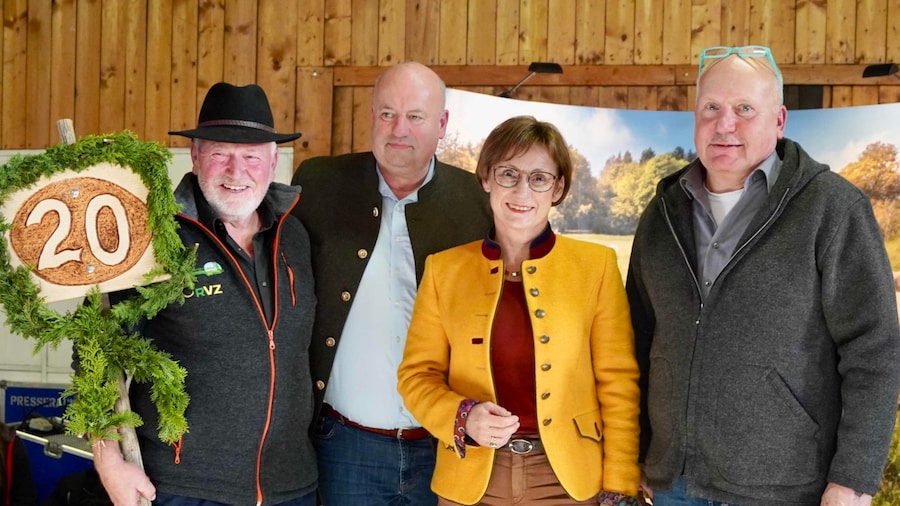 Drei Männer und eine Frau posten für des Bild. Ein Mann hält eine Schild mit der Aufschrift 20.