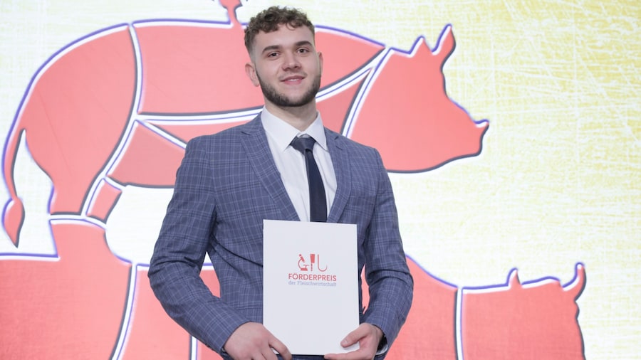 Alex Deneng lächelt und hält stolz seine Urkunde mit dem Titel Förderpreis der Fleischwirtschaft vor sich.