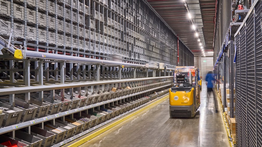 Im Lager werden Kleinartikel nach Auftrag eines Marktes vom Kommissionierer in Boxen auf seinem Flurförderfahrzeug gepackt.