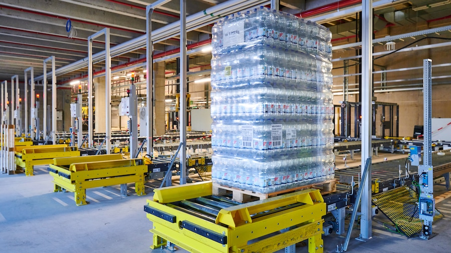 Eine ganze Palette mit PET-Sprudelflaschen wird im Wareneingang angenommen und auf einem Rollenförderband weiterbefördert. 