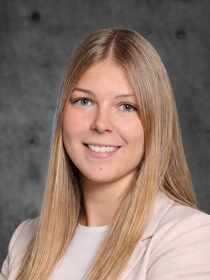 Portrait von Rebecca Moser. Sie hat blonde lange Haare, blaue Augen und trägt ein rosa Jacket.