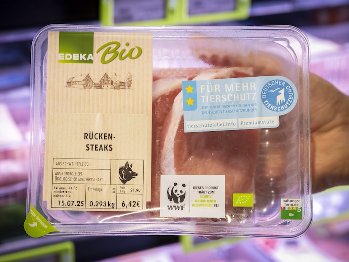 Fleischverpackung mit Angabe zur Haltungsform in der Hand eines/einer Kund:in.